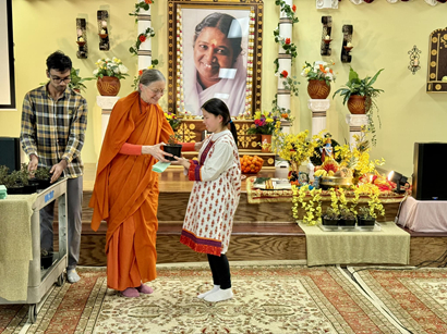 Swamini Ambikamrita Prana gifts saplings to a young devotee